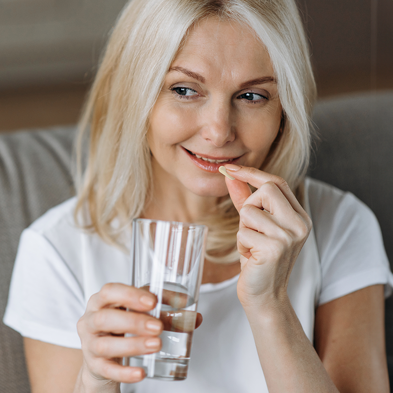 Woman taking her daily supplement with water